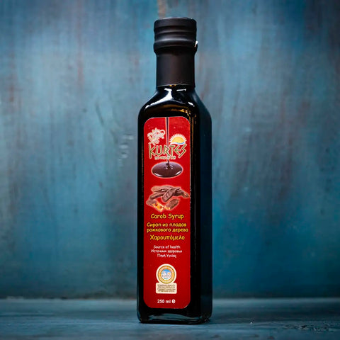 Carob Sirup der Kräftige im blauen Ambiente – intensiver, süßer Sirup aus Johannisbrot mit vollem Aroma, perfekt für mediterrane Desserts und Getränke.